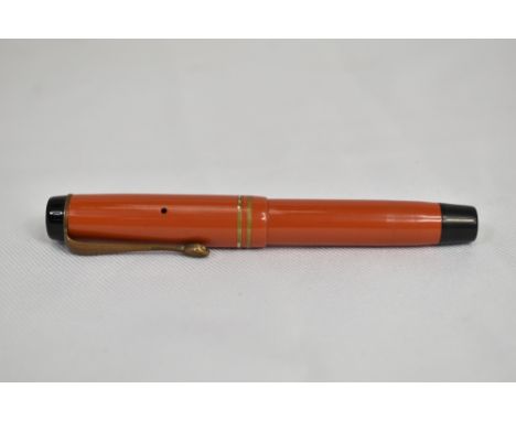A Parker Streamlined Junior Duofold button fill fountain pen in coral red with two rings to the cap and snakes head clip  hav