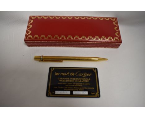 A Cartier Must de Cartier ballpoint pen in a gold metal with tri-colour  banding on lid, with reeded design to body. In origi