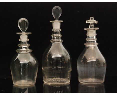 Two Georgian clear glass decanters of plain Prussian form with three rings to neck, one with lozenge stopper, together with a