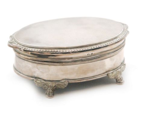 A hallmarked silver oval trinket box raised on four claw and ball feet below engine turned decorated hinged cover, length 12c