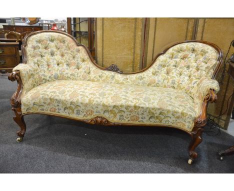 A Victorian carved walnut double spoon back chaise longue upholstered in buttoned pale floral tapestry on cabriole legs, leng