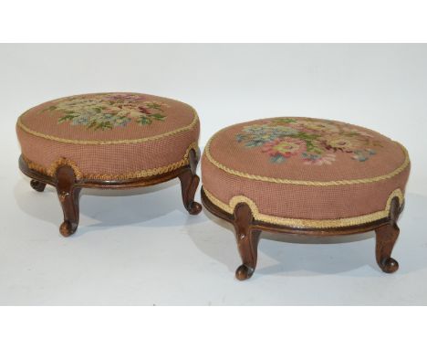 A pair of Victorian foot stools of circular form with carved exposed walnut frames and scroll feet, upholstered in woolwork t