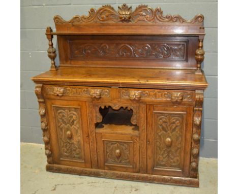 A Victorian carved oak sideboiard fitted with two lion mask handled drawers above a cupboard and central recess on a plinth b