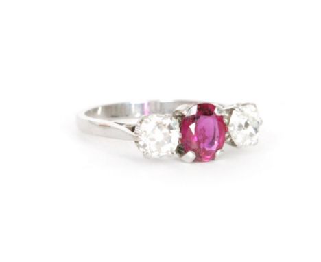 An early 20th Century ruby and diamond three stone ring, central oval ruby flanked by old cut diamond, all stones claw set to