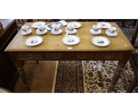 An early 20th century light oak framed writing table of oblong form with shaped top, three drawers under with brass drop hand