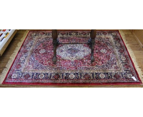 A Middle Eastern-style red ground drawing room carpet with multicoloured floral and foliate depictions with a double border a