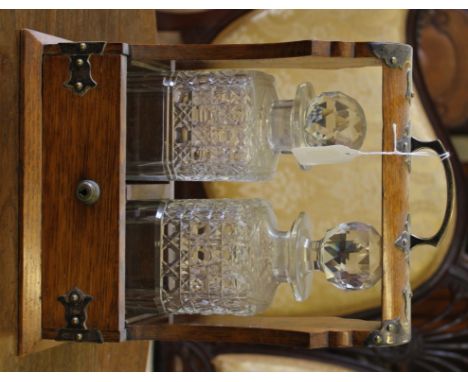 An early 20th century light oak and brass bound Tantalus with two square based decanters and stopper, 32cm x 24cm £40-60