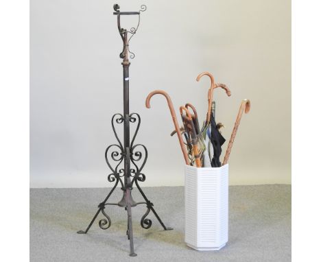 A collection of walking sticks, in a white stick stand, together with an iron oil lamp stand