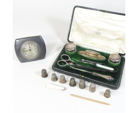 An early 20th century Tudric pewter travelling clock, 01468, 8cm, together with a cased silver manicure set and various thimb