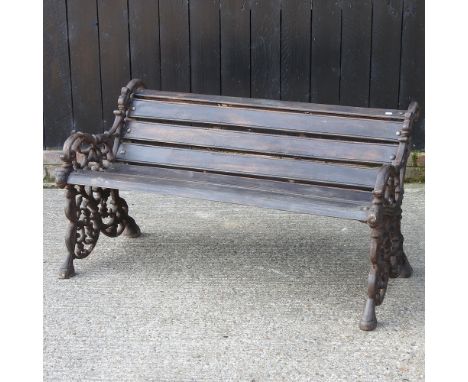 A modern black painted iron and wooden garden bench, of Victorian design, 123cm