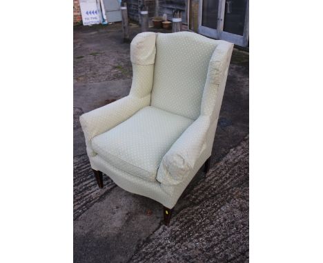 An Edwardian low seat wing back armchair, upholstered in a light green fabric 