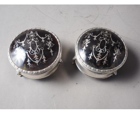 A pair of circular silver and tortoiseshell dressing table hinged boxes, on three cabriole supports, 2 3/4" dia 