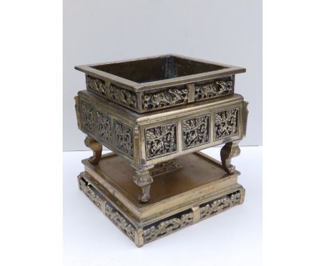 A Chinese square bronze censer, the sides having panelled decoration, on four curved feet to square bronze stand, 8.5” overal