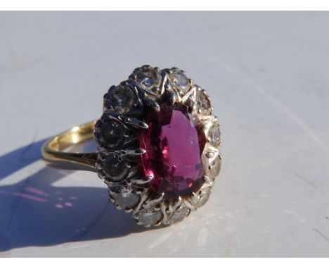 An oval ruby &amp; diamond cluster ring, the ruby weighing approximately 1.5 carats on yellow metal shank – '18ct &amp; Plat'