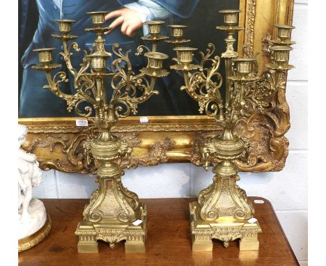 A Pair of Gilt Metal Six Light Candelabra, early 20th century, with mask handles and raised over scroll and gadrooned plinths