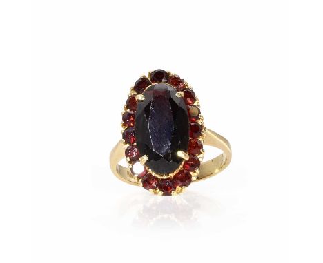 A Bohemian garnet cluster ring, the long oval cut principal garnet in a border of round cut garnets to an undercut gallery an