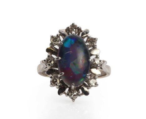 A white gold opal triplet and diamond cluster ring,an oval opal triplet claw set within a surround of eight cut diamonds betw