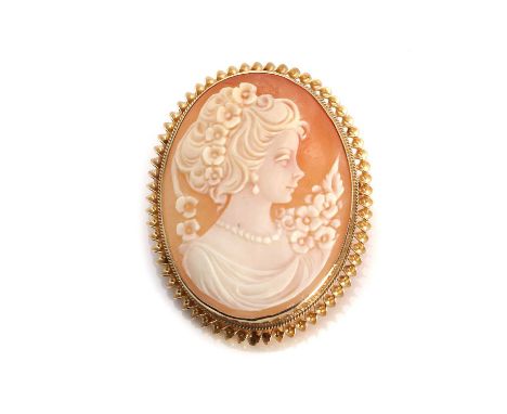A gold shell cameo brooch/pendant,the cameo depicting a young female figure and flowers, bezel set within a twist rope design