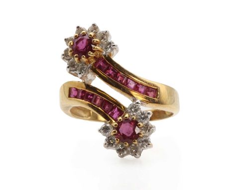 A ruby and diamond double cluster crossover ring, the alternating flower heads set with round mixed cut rubies within a surro