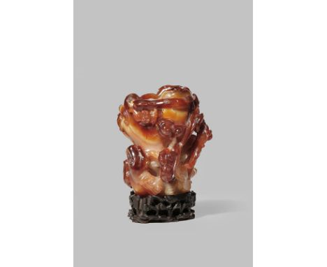 A CHINESE CARNELIAN-AGATE VASE 18TH/19TH CENTURY Carved as an old tree trunk overgrown with lingzhi fungus, with four bats ar