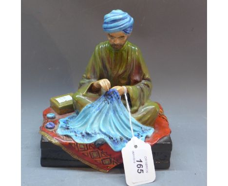 A ceramic figure of a carpet seller, Embroiderer of Kashmir, signed R  Johnson, H:18.5cm W:17cm D:13cm