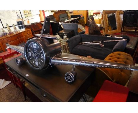 An Aviator style wall clock in the form of a plane. H-56cm, W-197cm, D-29cm 