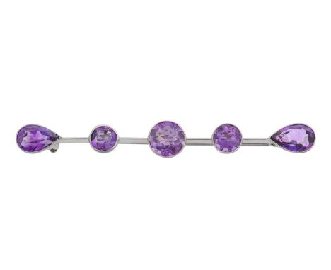 An Amethyst Brooch, a white plain polished bar with three graduated round cut amethysts centrally, terminating to pear cut am