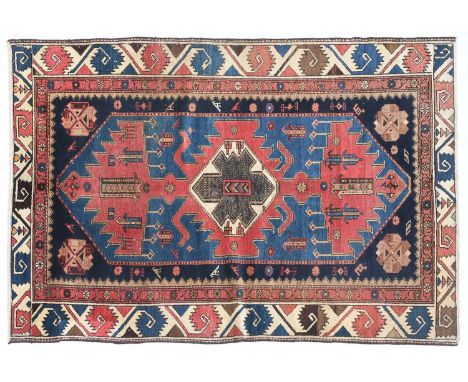 Enjilas RugKurdistan, Circa 1930The mid-indigo lozenge field with a serrated linked terracotta medallion flanked by zoomorphi