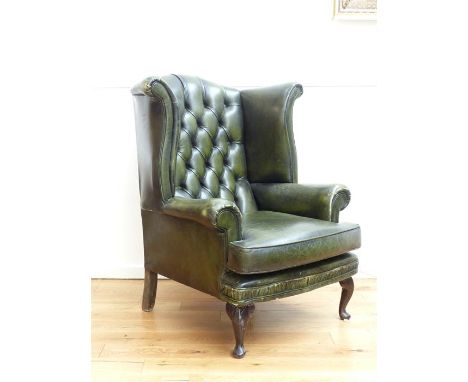 A green leather wing back armchair with button back, scrolling arms and raised on cabriole supports, 107 x 90 x 100cm.