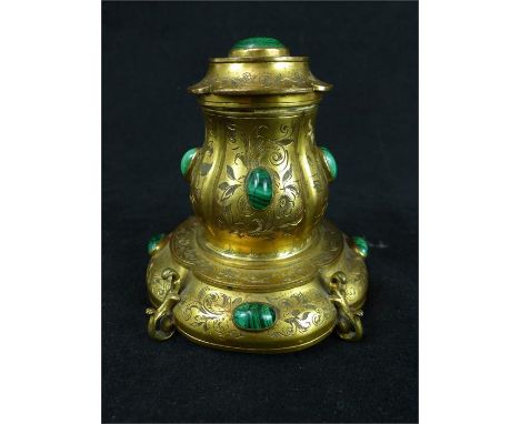 A late 19th century brass inkwell inset with malachite cabochons and chased floral arabesques.