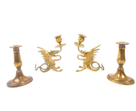 A collection of four brass candlesticks comprising of a 19th Century pair in the form of crouching phoenix figures and anothe