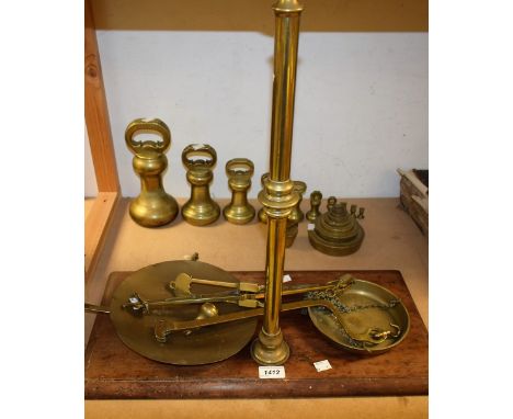 A matched set of ten brass bell weights, half ounce to fourteen pounds; another, stacking; a set of brass balance scales on w