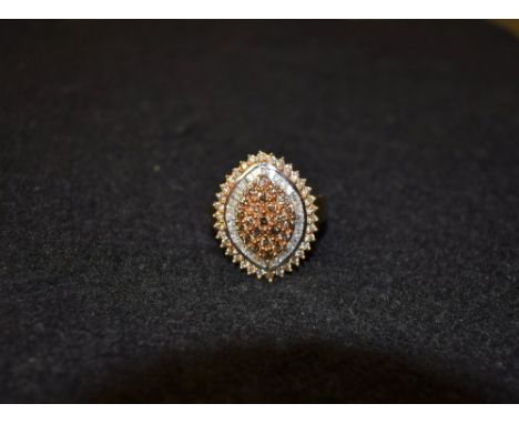 A cognac and white diamond cluster ring, central triple layer cluster of twenty three round cut cognac diamonds, surrounded b