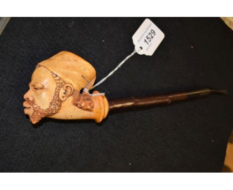 A 19th century Meerschaum pipe, the bowl carved as the head of a Nubian, wearing a fez, hawthorn shaft, 26cm long, c.1880