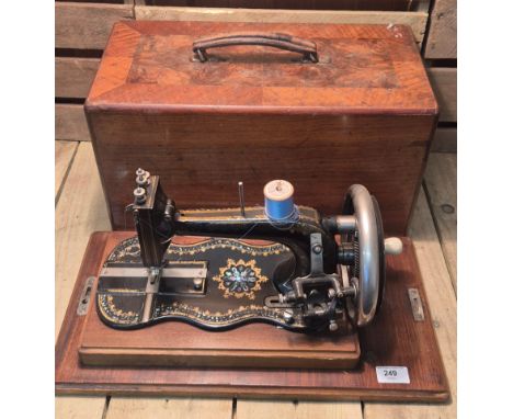 19th century fiddle base sewing machine. Hand crank. Mother of pearl inlay and gilt trims. Comes within a wooden travel case.