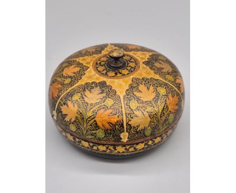 A hand painted Kashmiri papier mâché lacquerware box of round form with lid and finial top. Foliate band design on base. 12cm