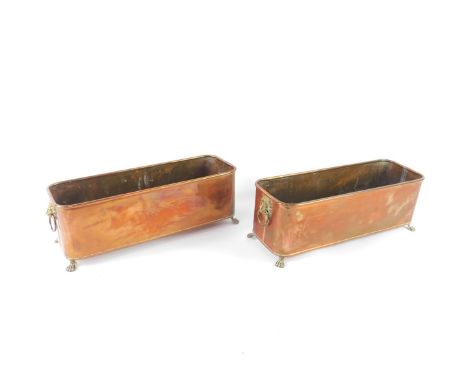 A pair of early 20thC copper planters, with brass lion's head and ring handles, raised on four brass paw feet, 16cm H and 49c