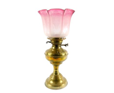 An early 20thC brass oil lamp, with glass chimney and etched and frosted clear to cranberry glass shade, 54cm H.
