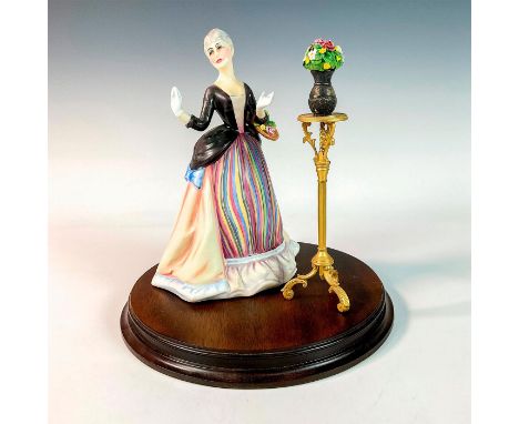 Porcelain figurine of a lady in a colorful striped dress with a vase of flowers on a brass stand. From the Gentle Arts Series