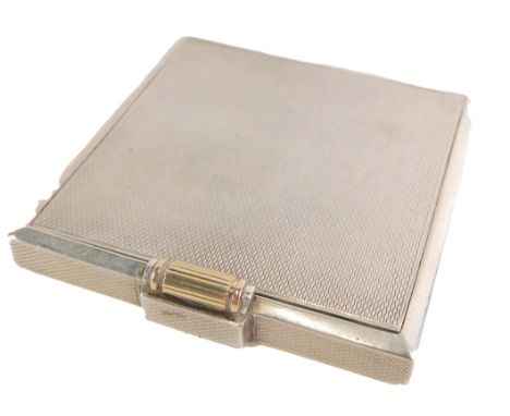 An Edward VII silver compact, of engine turned decoration, with thumb piece detail, opening to reveal a mirror plate and blus