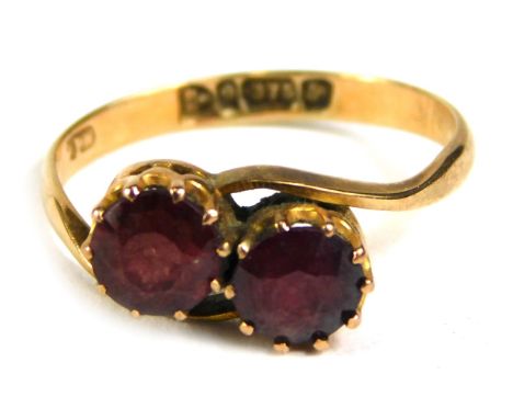 A 9ct gold twist ring, set with two garnets, ring size J½, 1.3g all in. 