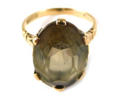 A 9ct gold smoky quartz dress ring, with oval smoky quartz, in six claw setting with V splayed shoulders, on yellow metal ban