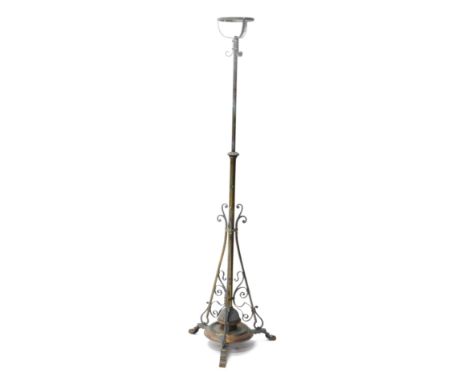 An early 20thC brass standard oil lamp, on adjustable stem, on tripod scroll base, with a copper rim, 160cm high. 