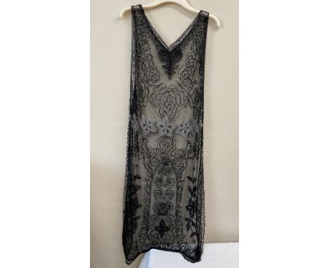 A 1920's beadwork dress, the net ground embellished with black and clear bugle beads. Approx 120 cm shoulder to hem.Condition