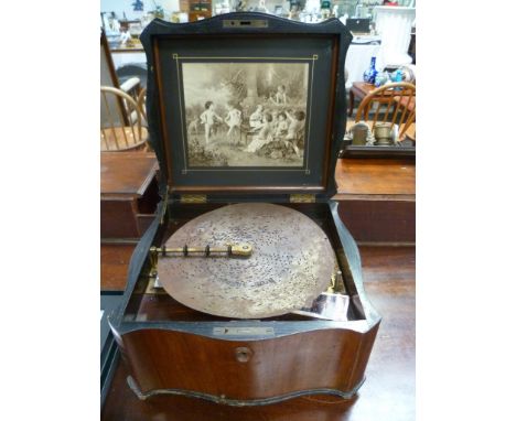 Early 20th Century walnut veneered inlaid table top polyphon, the serpentine hinge lid revealing an inset black and white pri