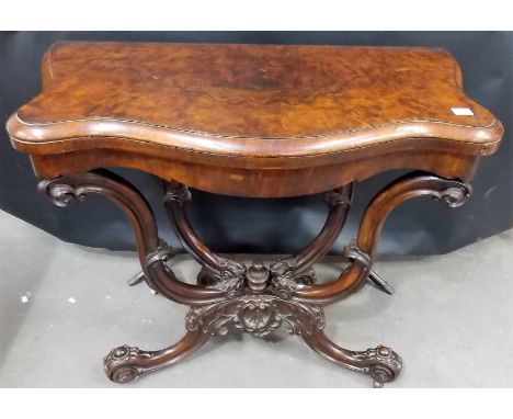 Victorian burr walnut veneered card table, on four scroll carved supports and four leaf carved outswept legs and casters. 