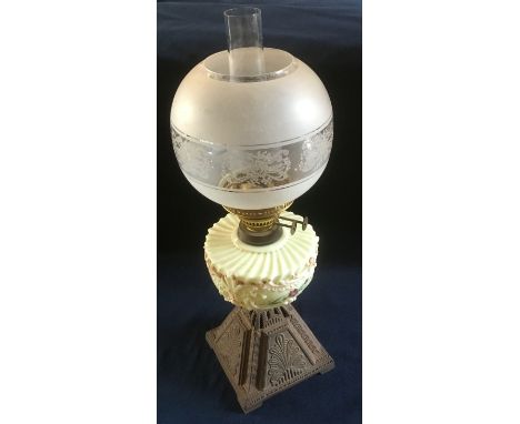 AN EDWARDIAN OIL LAMP  with opaque glass reservoir and cast iron base, 56cm high overall
