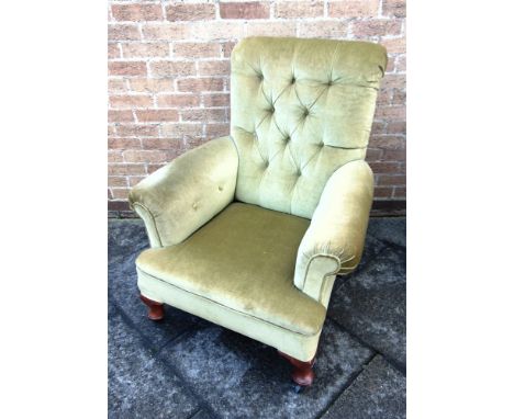 AN EDWARDIAN BUTTON UPHOLSTERED ARMCHAIR  with scroll arms, on cabriole supports with ceramic casters