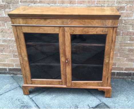 A WALNUT BOOKCASE  the glazed doors enclosing two adjustable shelves, on bracket feet, 110cm wide 37cm deep 103cm high