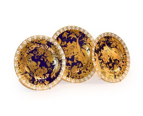 Royal Crown Derby, a set of three cobalt blue and gilt plates decorated with exotic birds (3)